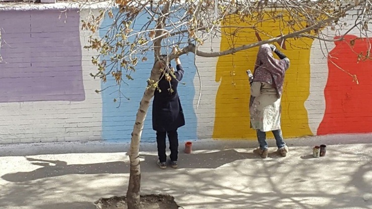 بانوان گرافیست درحال طراحی و رنگ‌آمیزی دیوارها برای نوروز؛ مشهد، دیوار ورزشگاه شهید بهشتی، خیابان یاس.