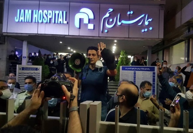 همایون شجریان که به‌تازگی داغ پدر را دیده است، روی سکوی جلو بیمارستان جم با بلندگوی دستی می‌گوید: «پدرم را در جوار حضرت فردوسی در مشهد و توس به خاک می‌سپاریم.» اما به ناگاه صدای برخی مردم بلند می‌شود: «استاد این کار رو نکن! همین تهران!»