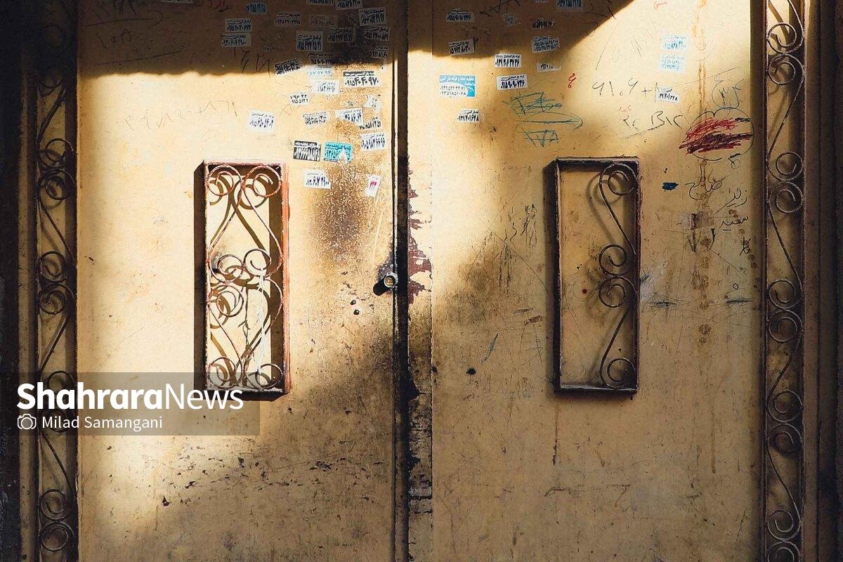 حتما آن تصویر عباس عطار از کیارستمی را دیده‌اید که وسط بَرّبیابان، سیاه‌پوش و چموش، خم شده و سرش را کرده لای چهارچوب دری نیمه‌باز؛ در آهنی زنگ‌زده‌ای در ناکجاآبادی ویران‌شده که هیچ خانه‌ای به آن وصل نیست. درها، فارغ از باز یا بسته بودن‌شان، حتی اگر وسط برهوتی پرت یا روی نوک قله کوهی بلند دیده شوند، آدم‌ها را امیدوار می‌کنند. هر دری کورسویی‌ست و روزنۀ امیدی چراکه پشت این در‌ها زندگی جریان دارد و به‌محض باز شدنش هُرم گرمای نفس‌های اهالی‌اش بیرون می‌زند. جان‌های امیدواری هر روز صبح این در‌ها را به امید روز‌های روشن‌تری باز و بسته می‌کنند.
این مجموعه دعوت به تماشای در‌های خانه‌هایی‌ست در محلۀ محروم «تاجرآباد» مشهد؛ جایی‌که مردمانش به سختی روزگار می‌گذرانند، اما همچنان تلاش می‌کنند و امیدوارند این در‌ها برای همیشه بسته نمانند و از خدای در‌های باز می‌خواهند که آن‌ها را از این آستانه بگذراند.